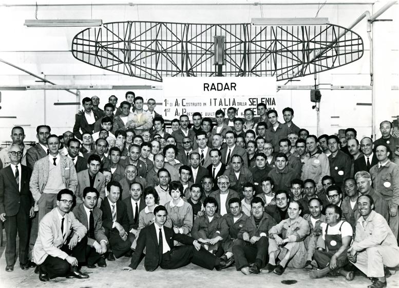 The Selenia radar design and production team. In the background, the MIM-23A HAWK anti-aircraft system produced at the  Fusaro (Naples) site and launched in 1961.